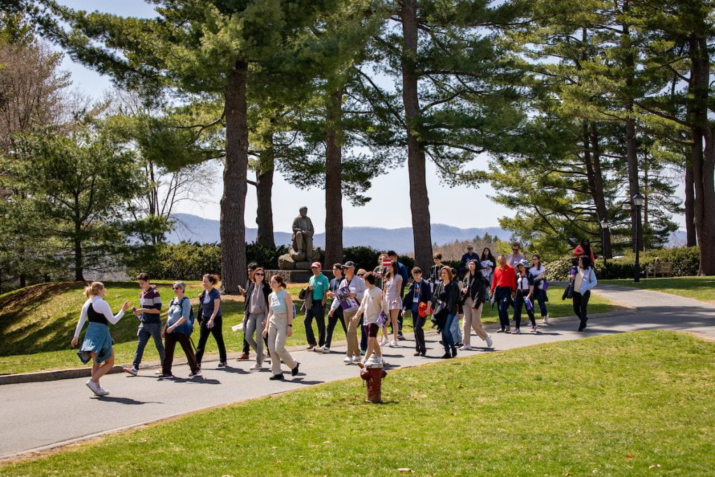 a student tour guide leads a group of visitors across the quad on a sunny day